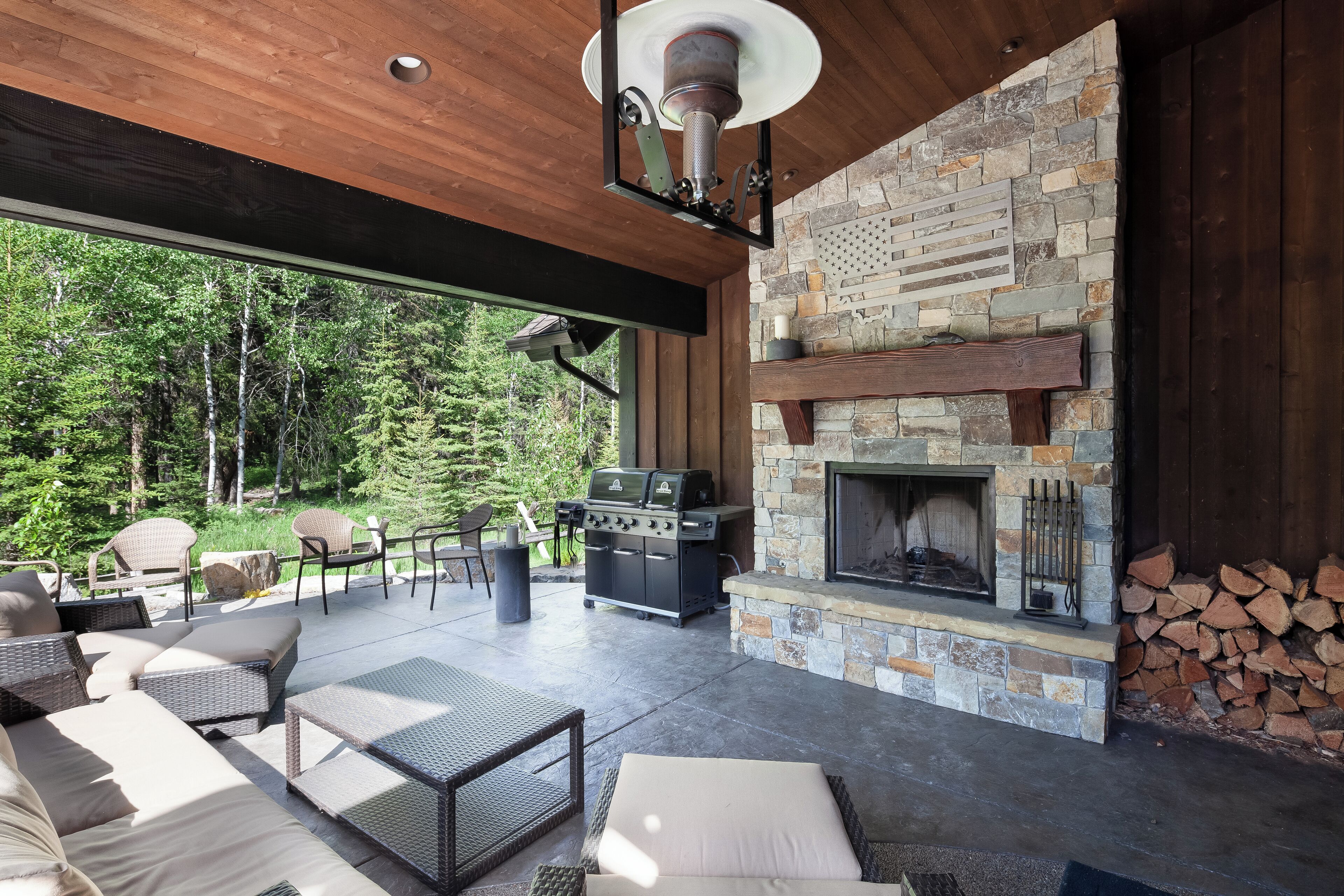 Un patio exterior con chimenea de piedra, zona de barbacoa y asientos cómodos.