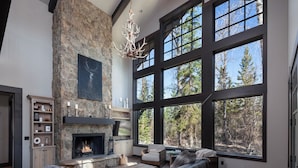 A spacious living room with a stone fireplace, large windows, and a leather sofa. - Lodge at Whitefish Lake (Whitefish)