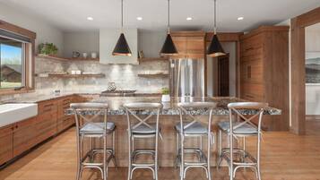 Een moderne keuken met een centraal eiland, barkrukken, roestvrijstalen apparatuur en houten keukenkastjes.