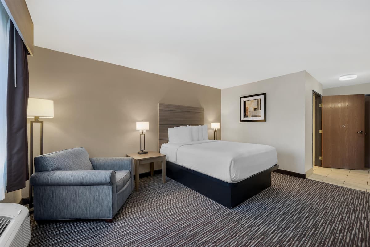 A hotel room with a bed, a sofa, a desk, and a nightstand.