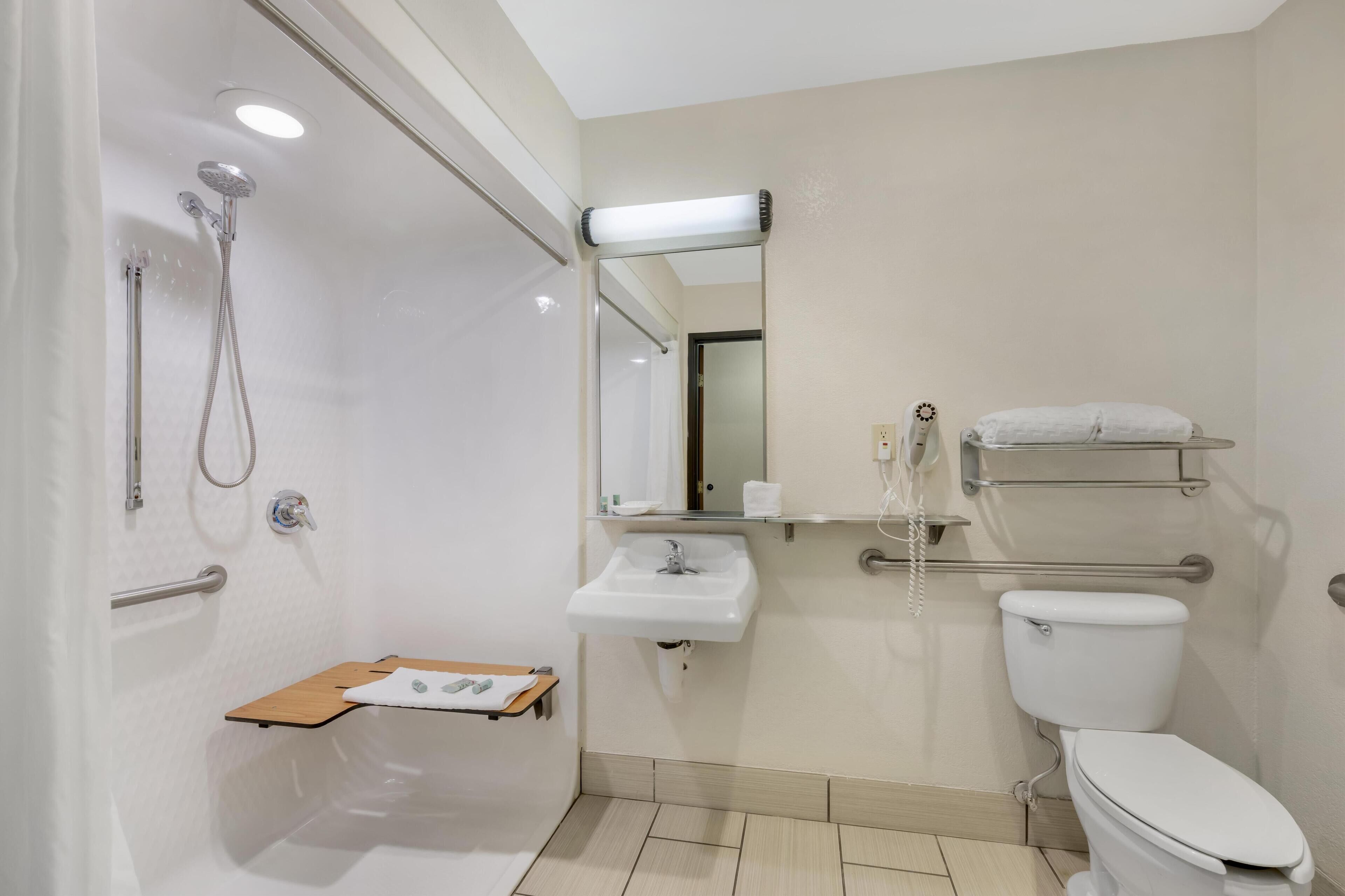 Une salle de bain équipée d’une douche, de toilettes, d’un lavabo et d’un miroir.
