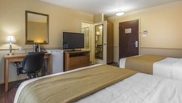 A hotel room with a bed, a desk with a computer, a television, and a wardrobe.