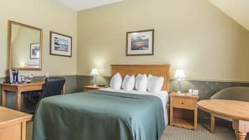 A hotel room with a bed, a desk, a chair, a nightstand, and two lamps.