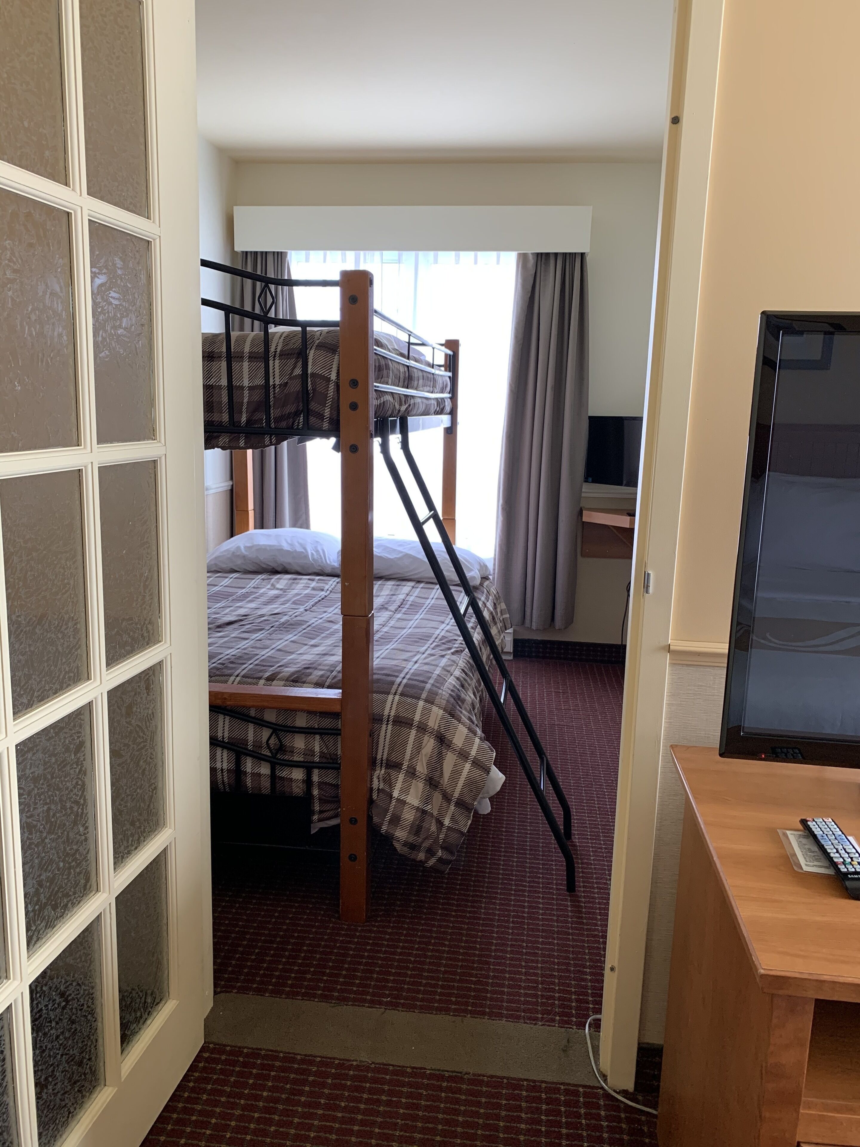 Una habitación con una cama litera, un escritorio con computadora y un televisor.