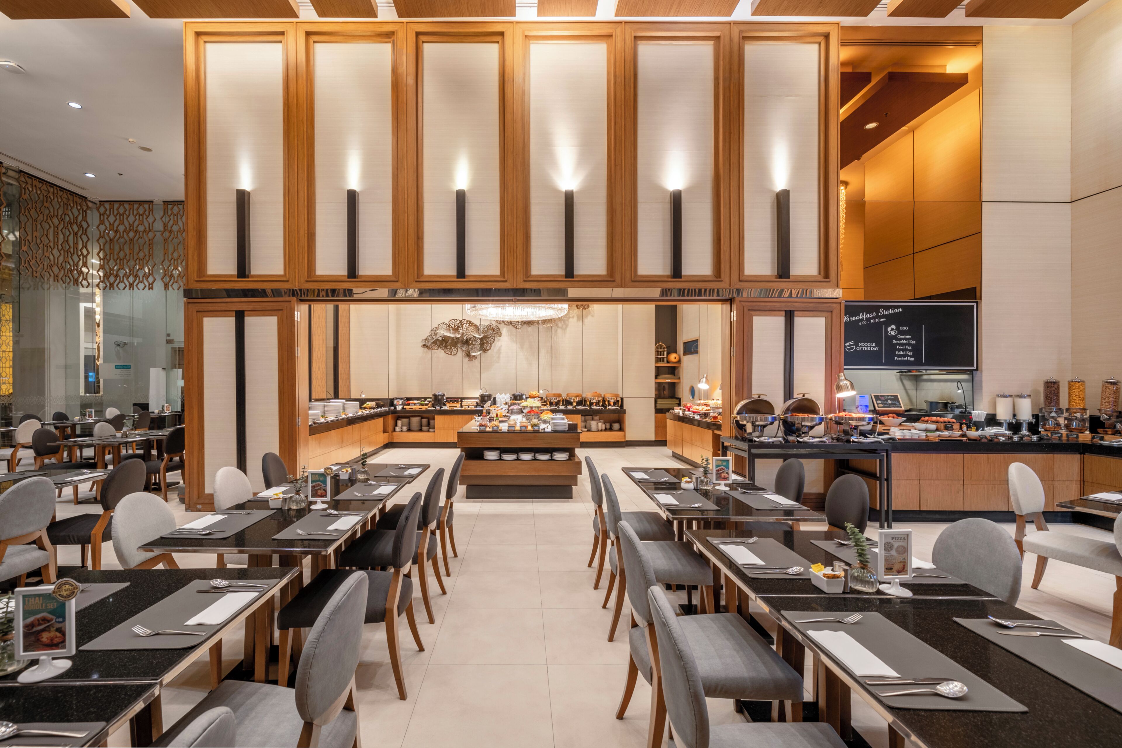 A modern restaurant with a central island, multiple dining tables, and a bar area.