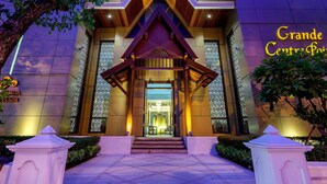 A hotel entrance with a modern design, featuring a prominent entrance with steps, a wooden facade, and a sign reading "Grande Centre Point". - Grande Centre Point Ploenchit (Bangkok)