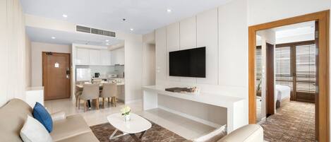 A modern living room with a flat-screen TV, a sofa, a coffee table, and a dining area.