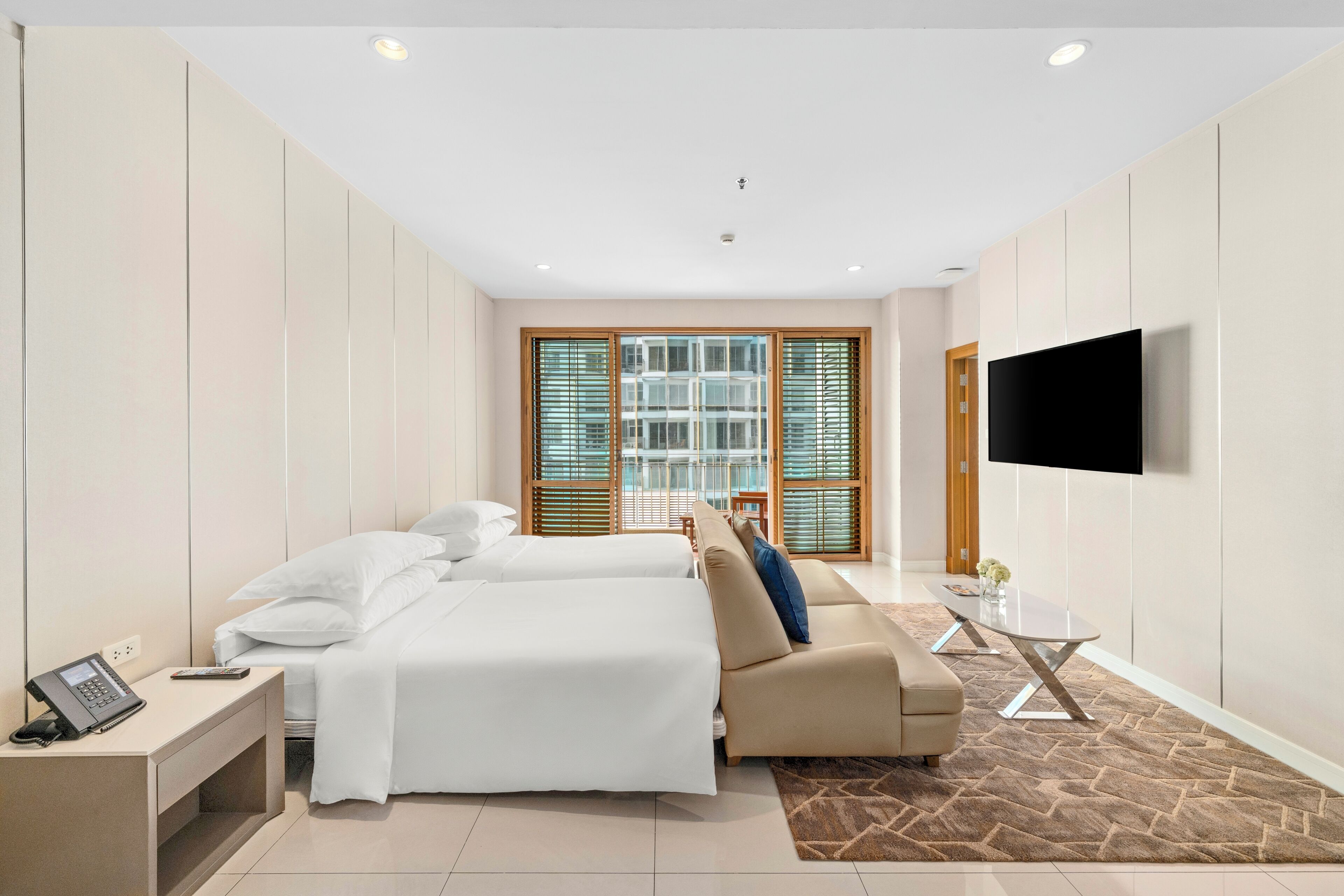 Una habitación de hotel con dos camas, un sofá, un televisor y un escritorio con un teléfono.