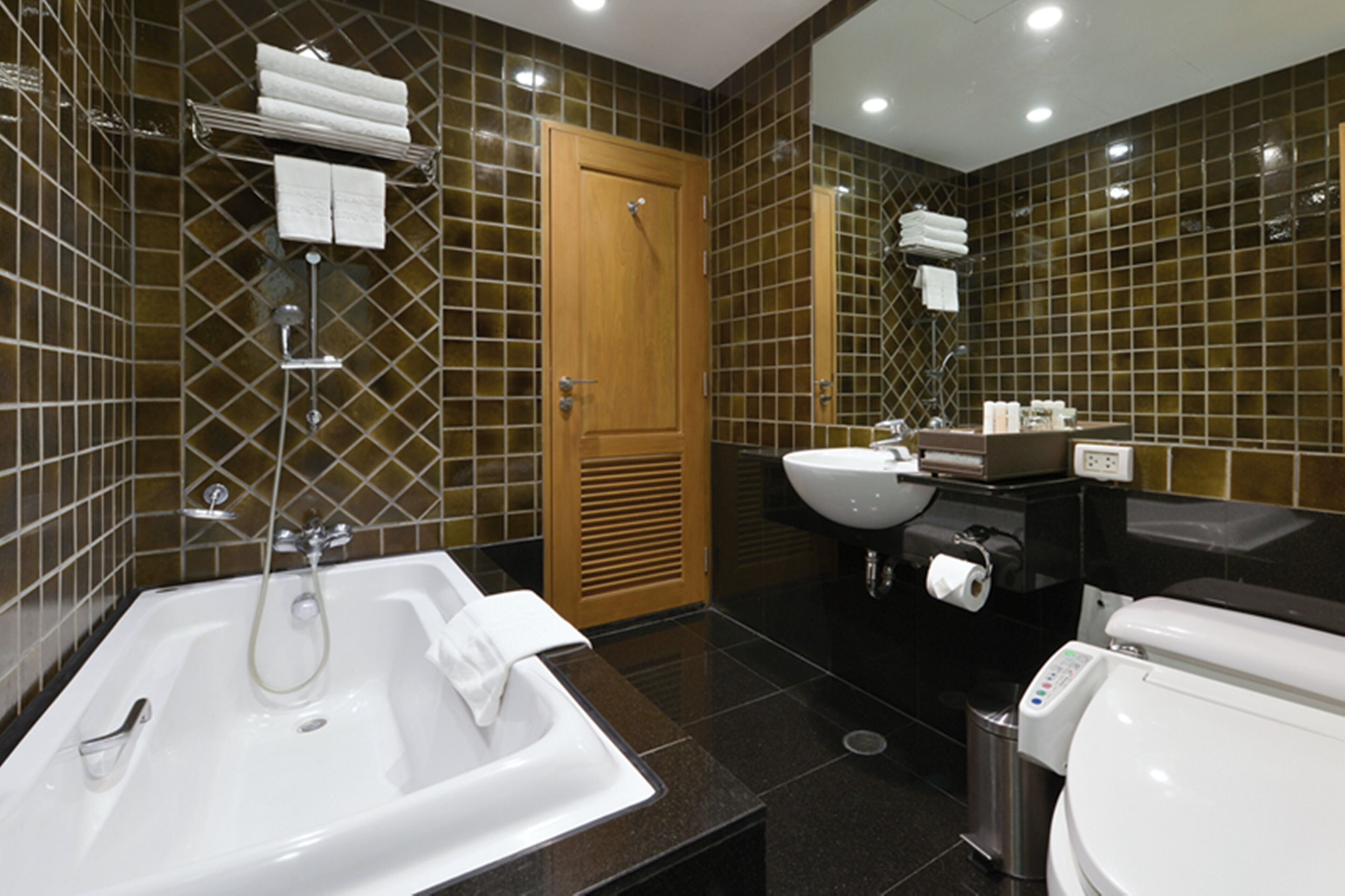 Un baño moderno con bañera, lavamanos, inodoro y espejo.