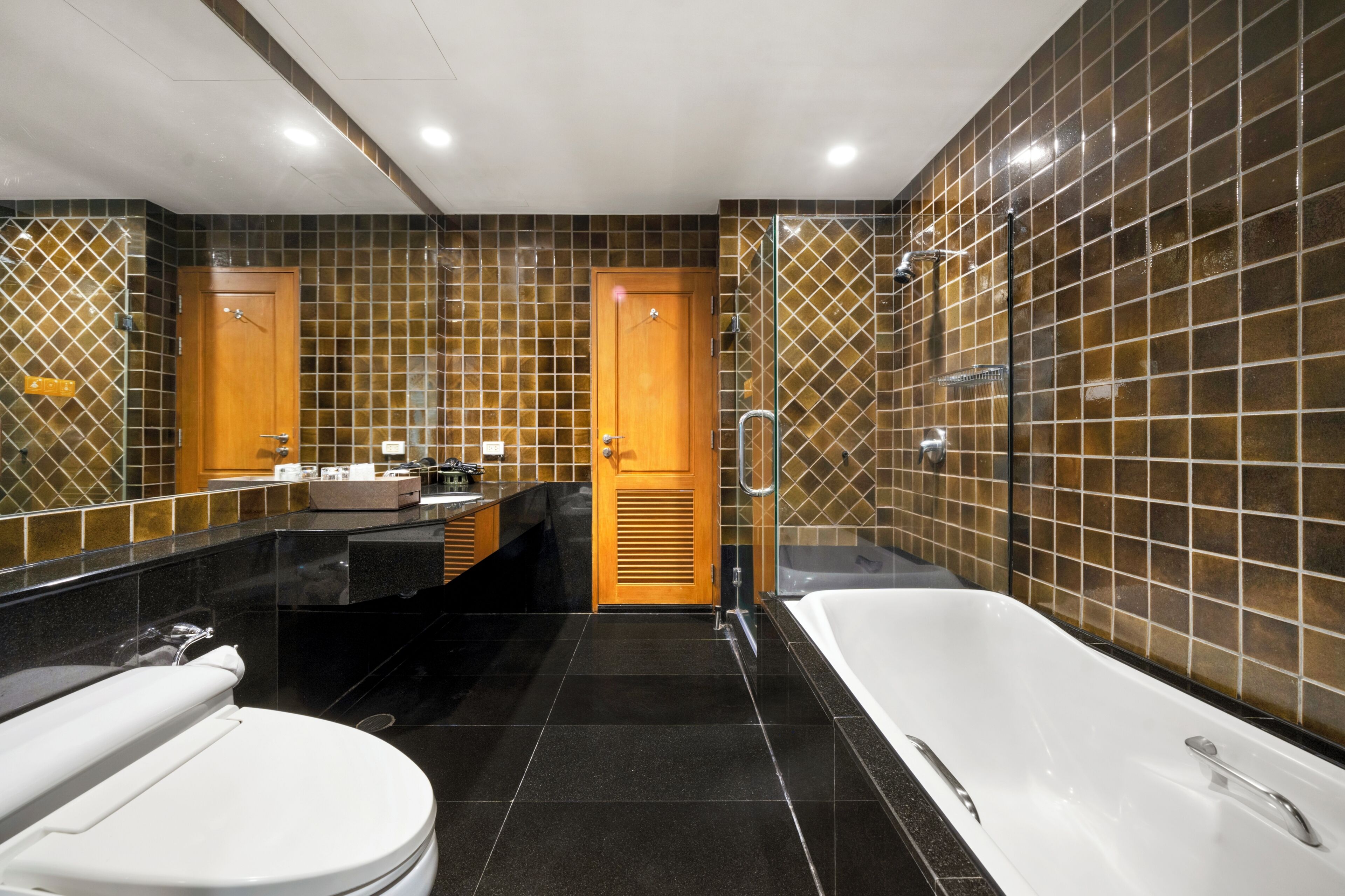A modern bathroom with a bathtub, toilet, vanity, and a shower area.
