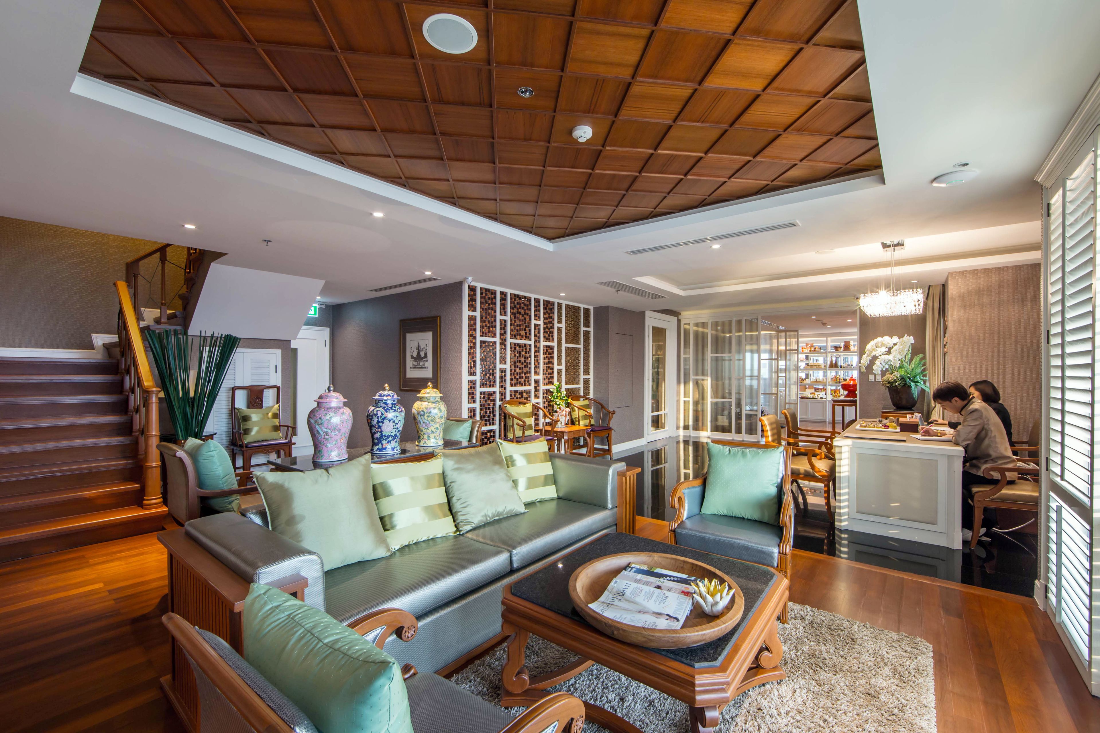 A spacious living area with a wooden ceiling, a sofa set, a coffee table, and a dining area with chairs and a table.