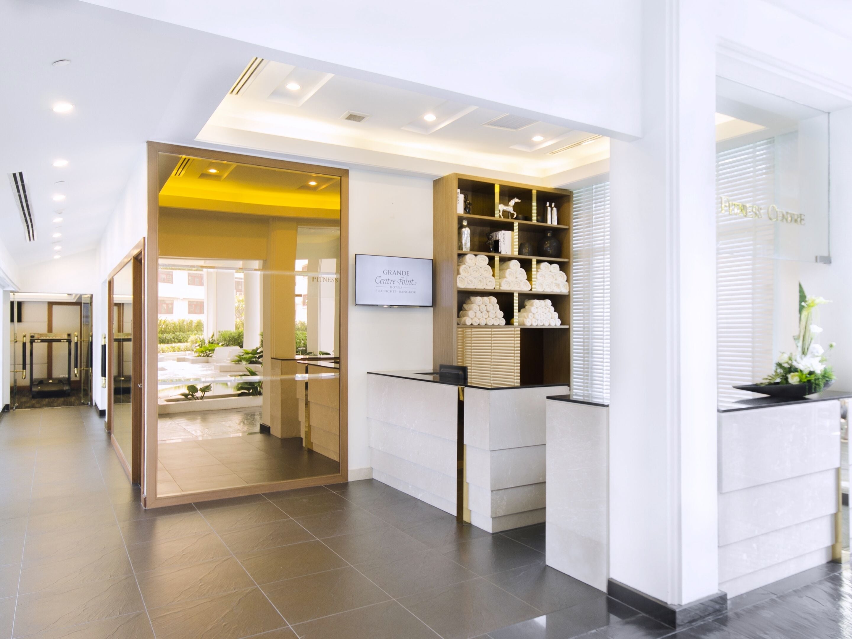 A hotel reception area with a modern design, featuring a reception desk, a glass partition, and a display of toiletries.
