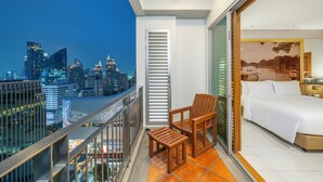 A balcony with a city view, a bed, and a chair. - Grande Centre Point Ploenchit (Bangkok)