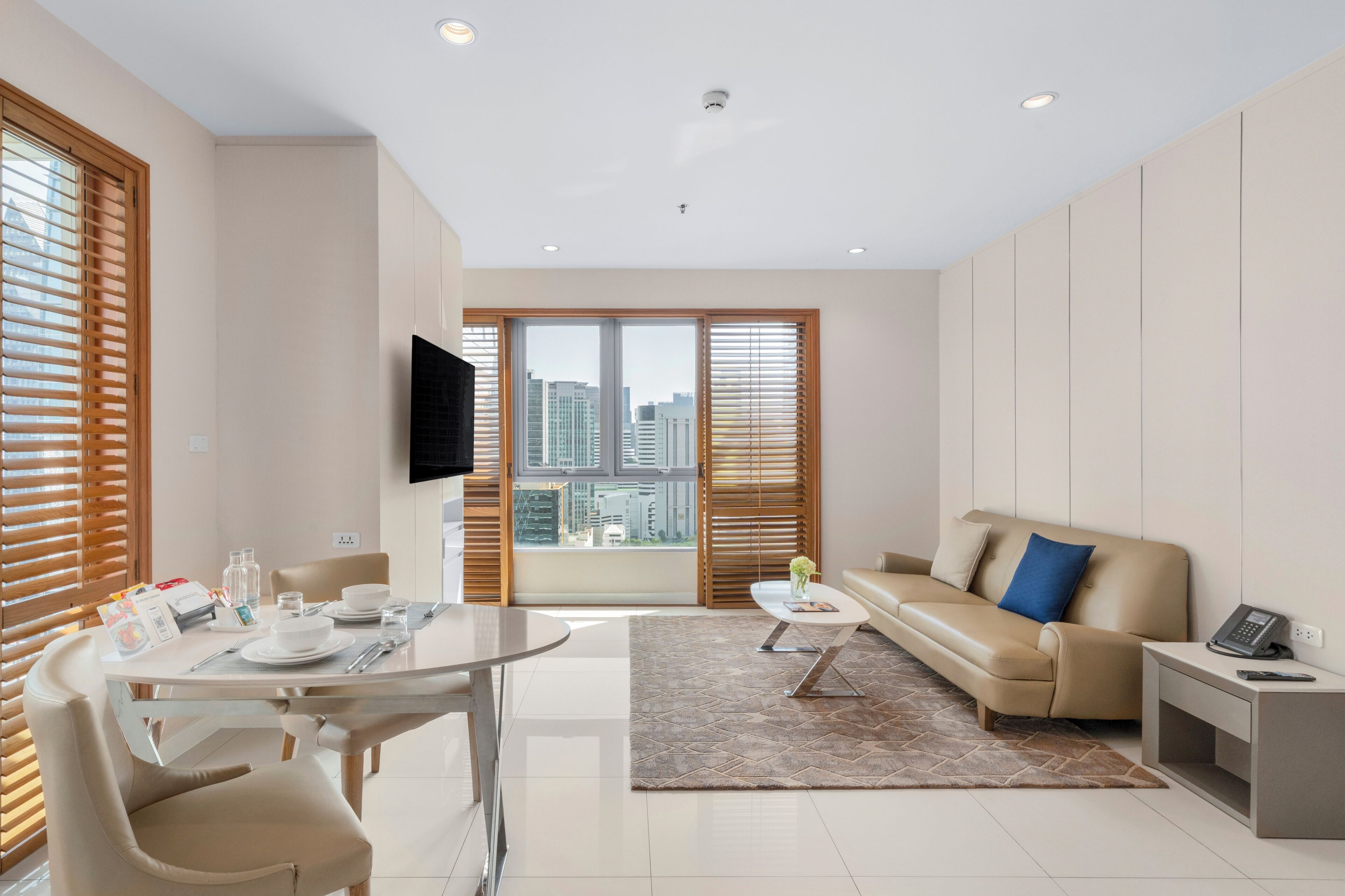 Un salon moderne comprenant un coin repas, un canapé, une table basse et un téléviseur à écran plat fixé au mur.