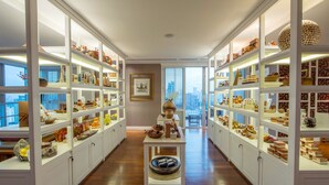 A spacious, well-lit walk-in closet with white shelving units displaying various items. - Grande Centre Point Ploenchit (Bangkok)