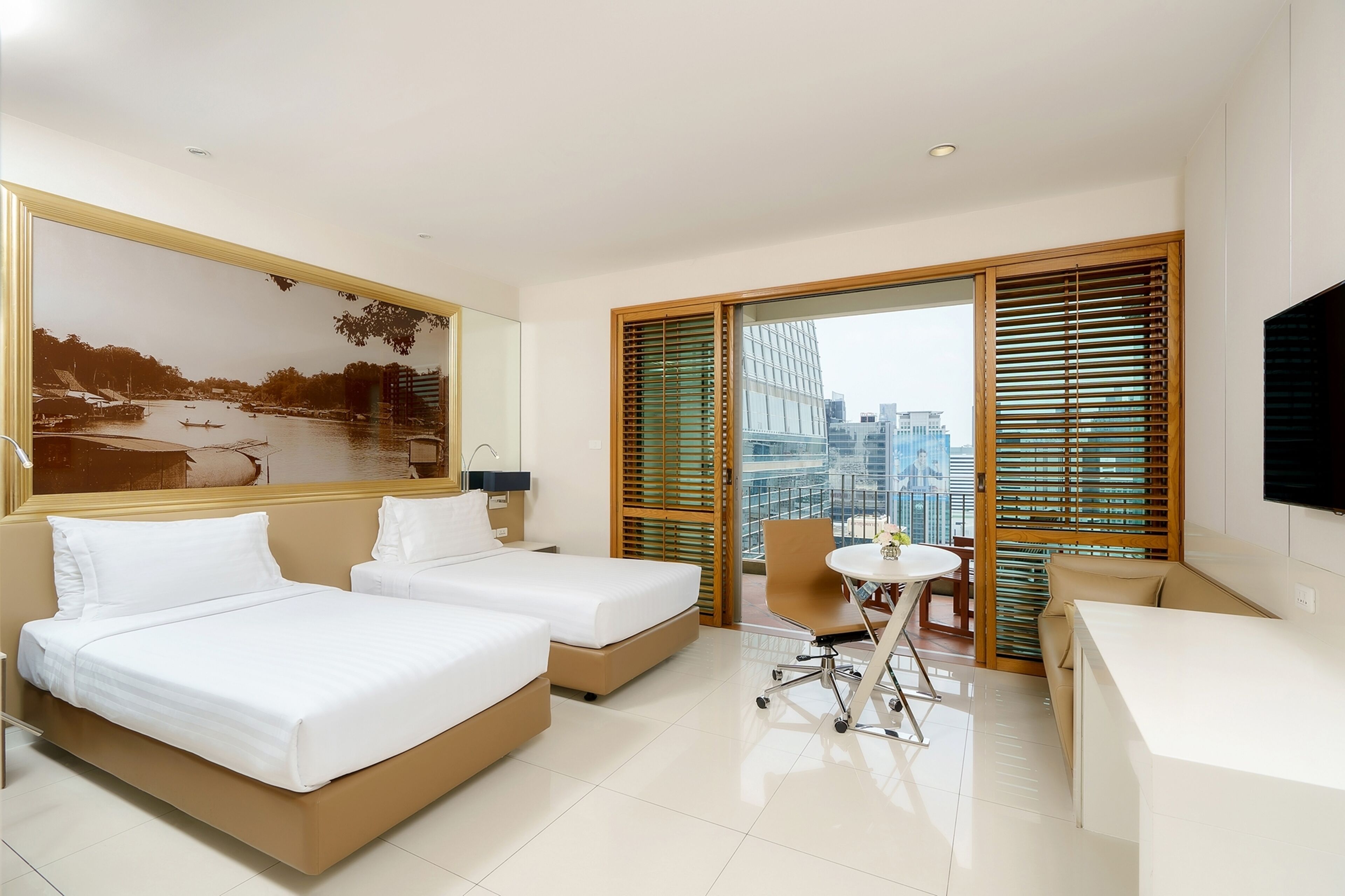 A hotel room with two beds, a desk, a chair, a TV, and a large window with blinds.