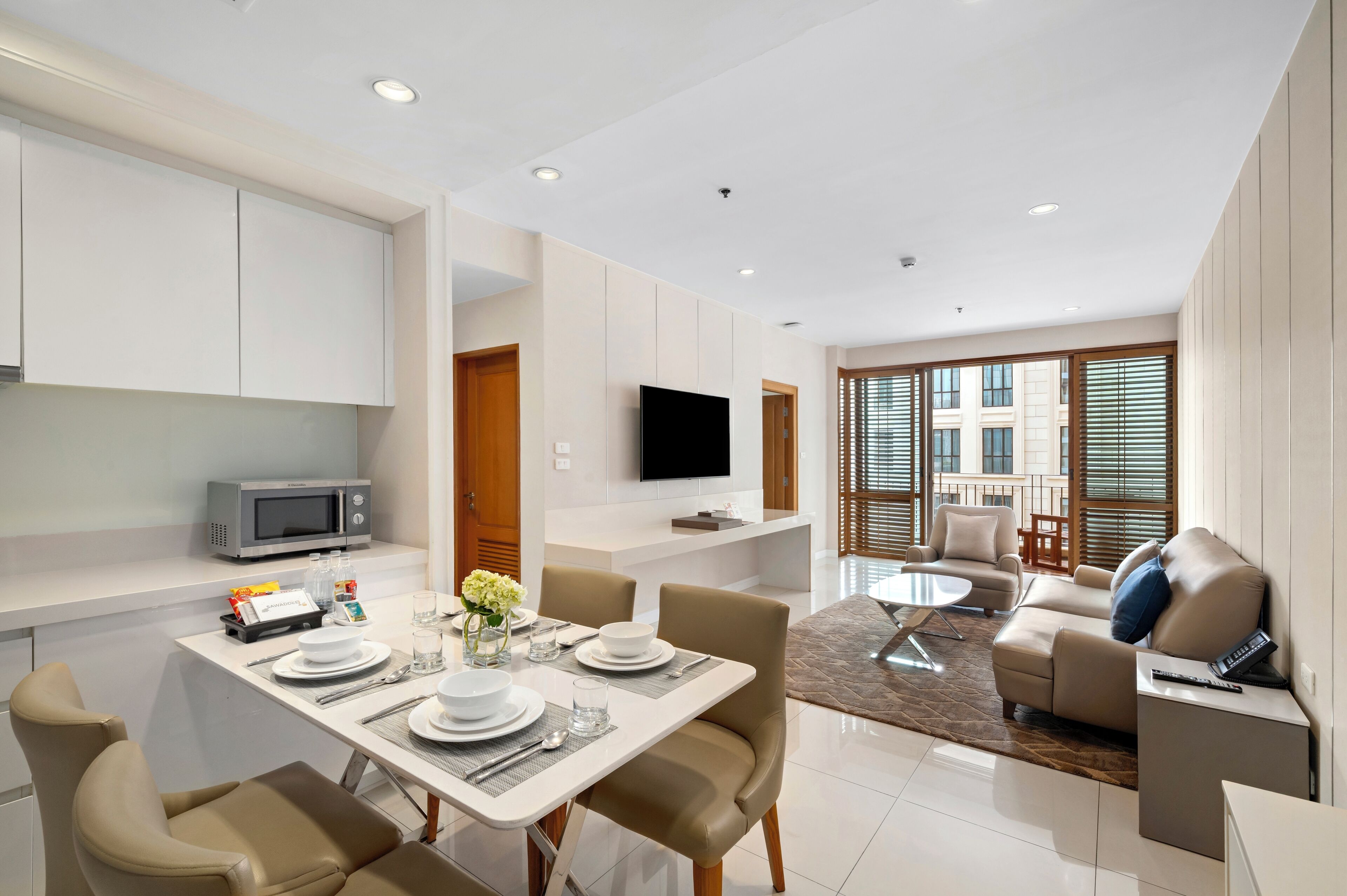 A modern living room with a dining area, a flat-screen TV, and a sofa.