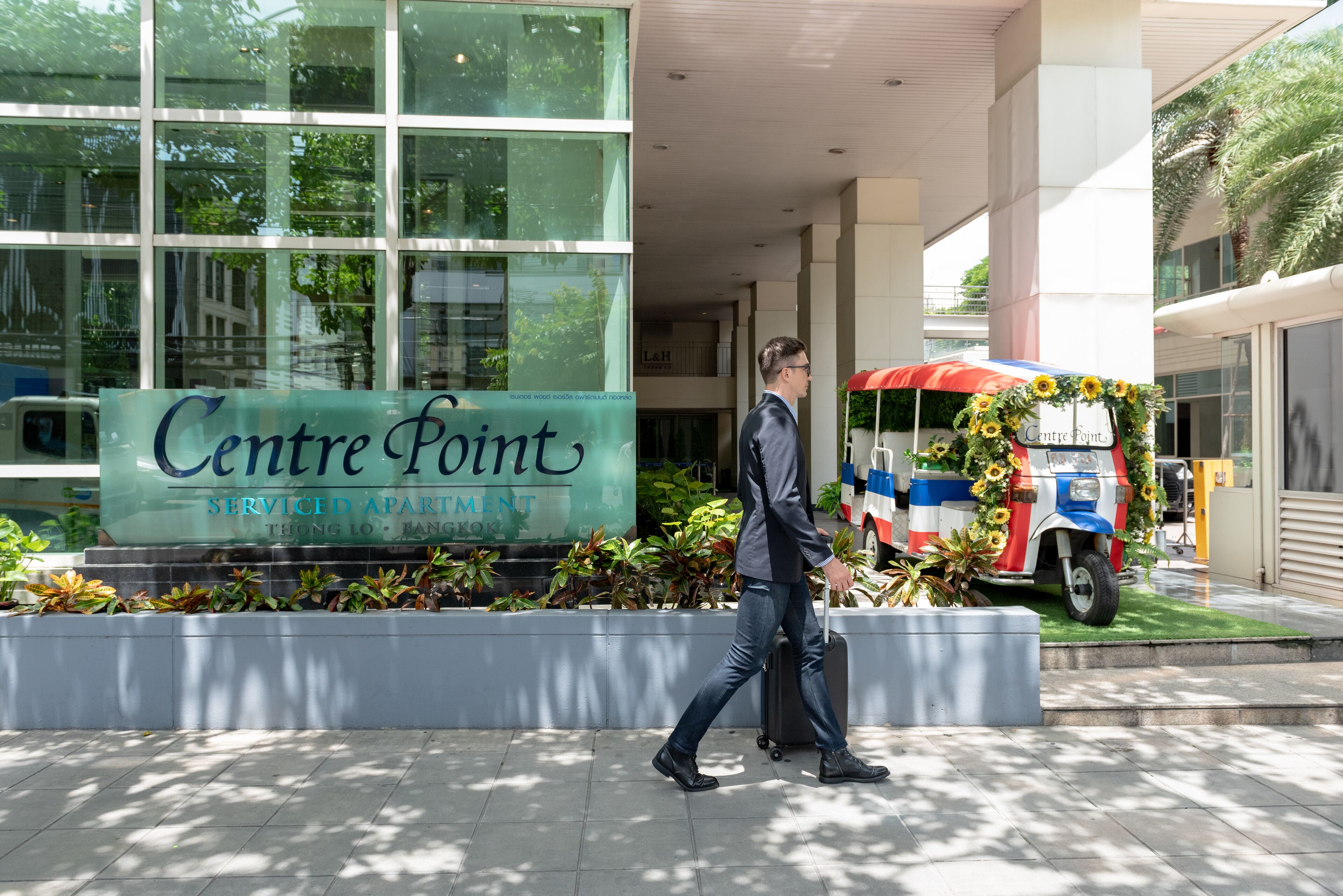 A hotel entrance with a sign reading "Centre Point" and a vehicle decorated with sunflowers.