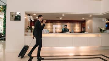 A hotel reception area with a reception desk, a sign indicating a conference room, and a receptionist.