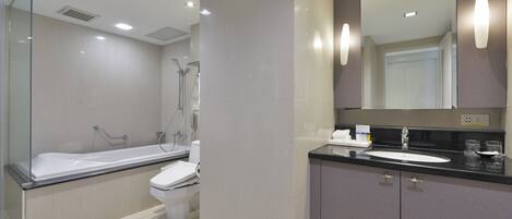 Un baño moderno con bañera, inodoro y tocador con espejo.