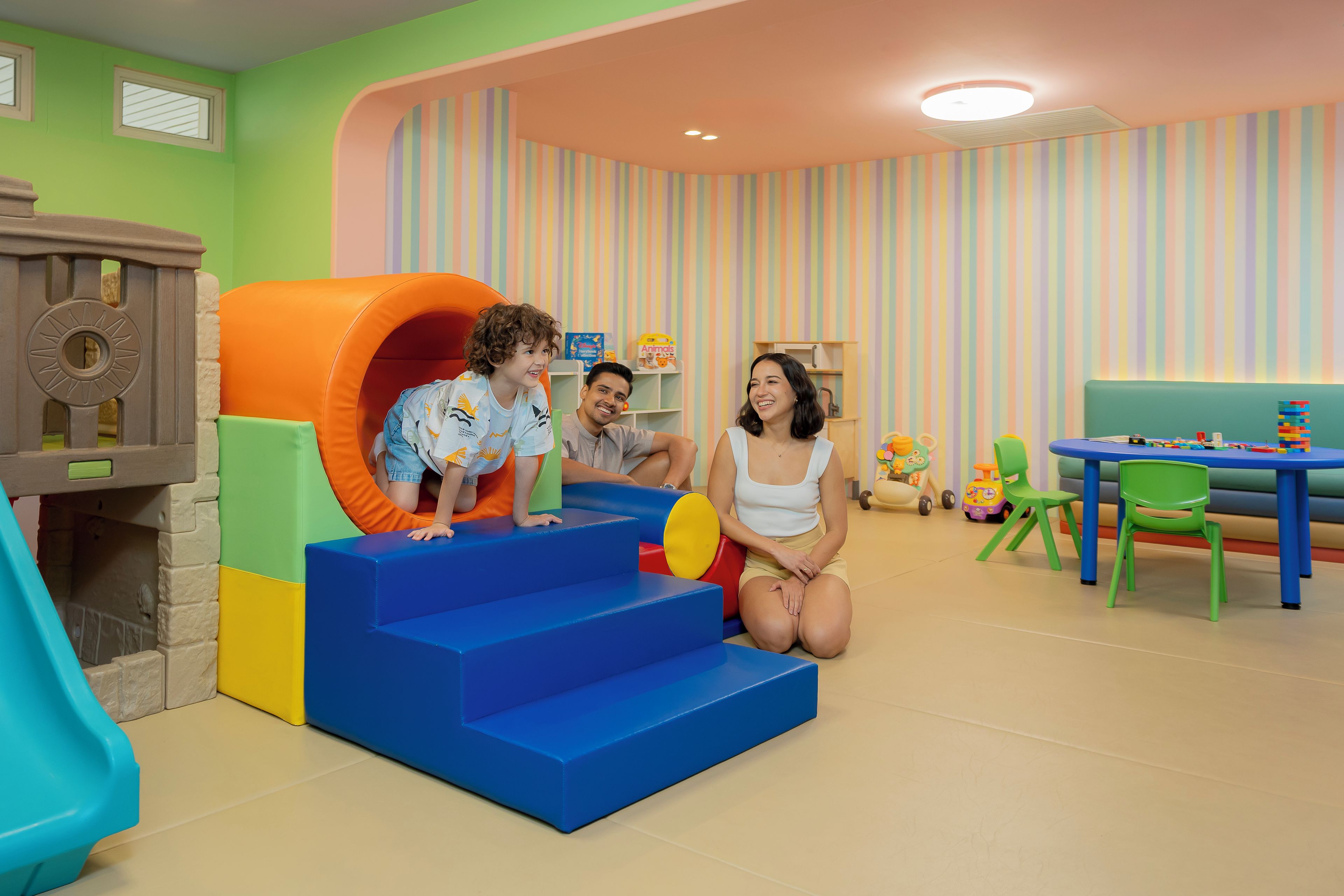 A play area with colorful play structures, a slide, and a play table with toys.