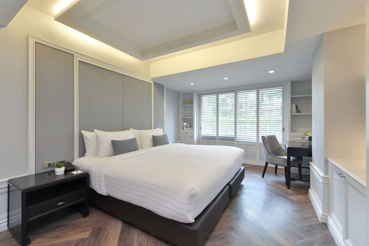 A modern bedroom with a large bed, bedside tables, a desk, and a chair.