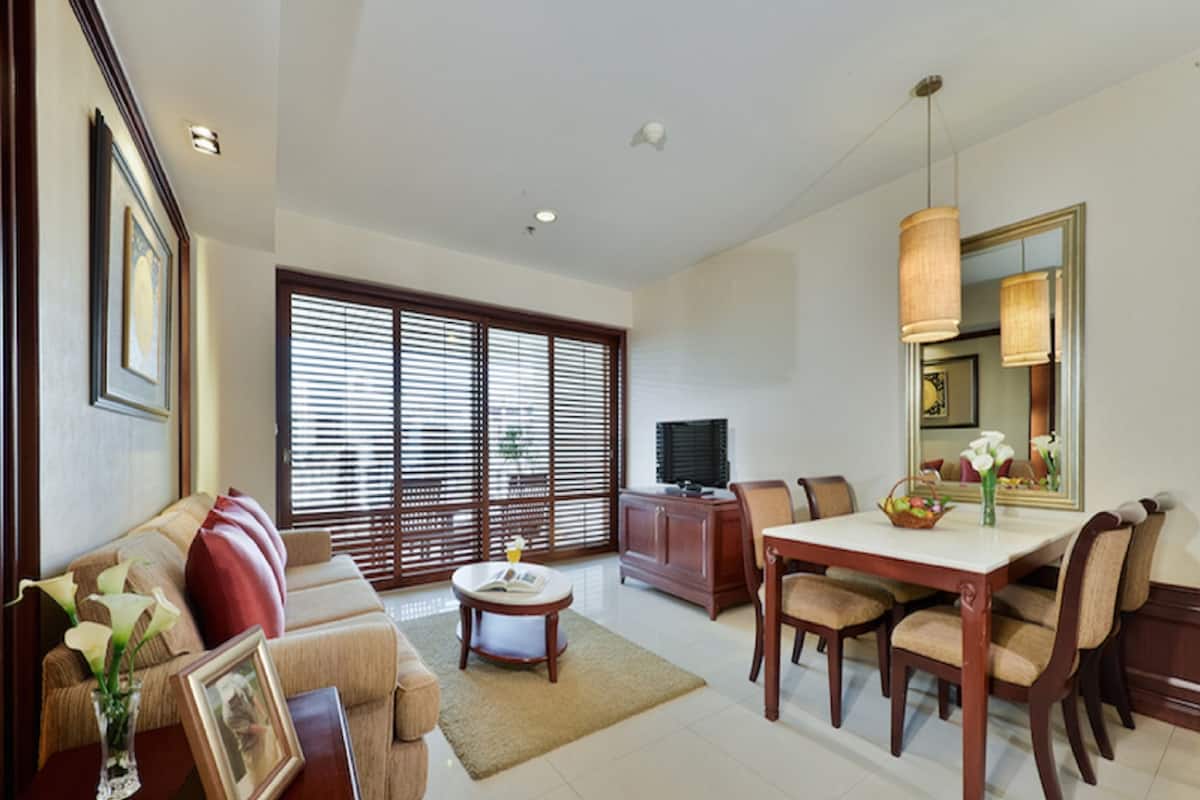A spacious living room with a sofa, coffee table, and dining area with chairs and a table.