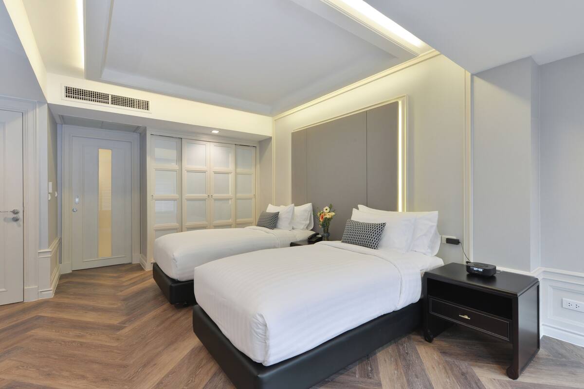 A hotel room with two beds, a nightstand, and a large mirror.