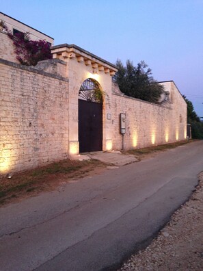 A stone building with a dark entrance, illuminated by ground lights, and a signboard to the right. - Montepaolo Dimora di Charme (Conversano)