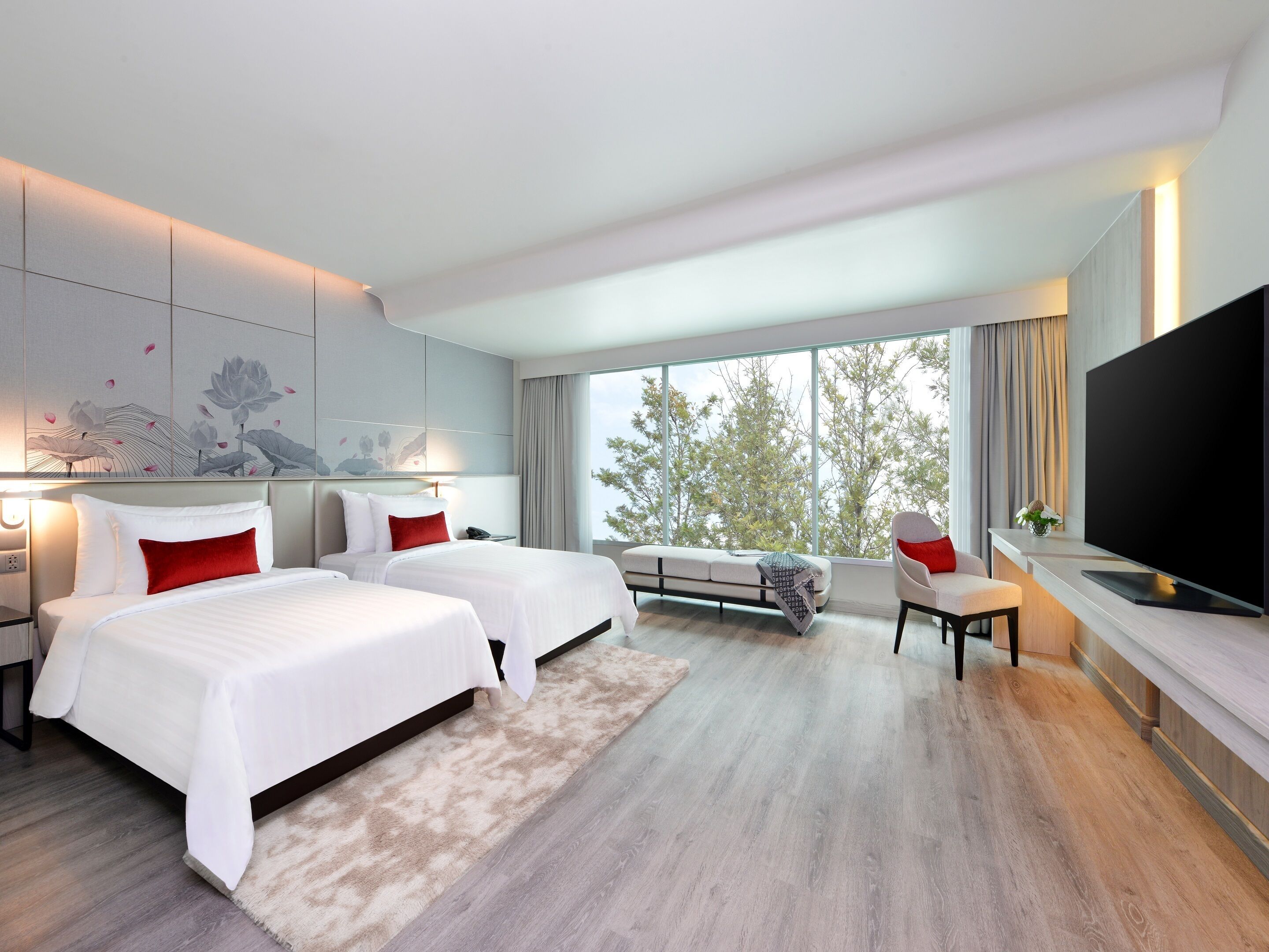 A modern hotel room with two beds, a large window, a flat-screen TV, and a sofa.
