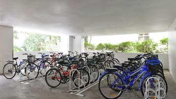 Un espacio cubierto para estacionar bicicletas, con varias bicicletas y una bicicleta eléctrica azul.