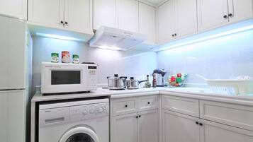 A compact kitchen with white cabinets, a microwave, a washing machine, and a stove.