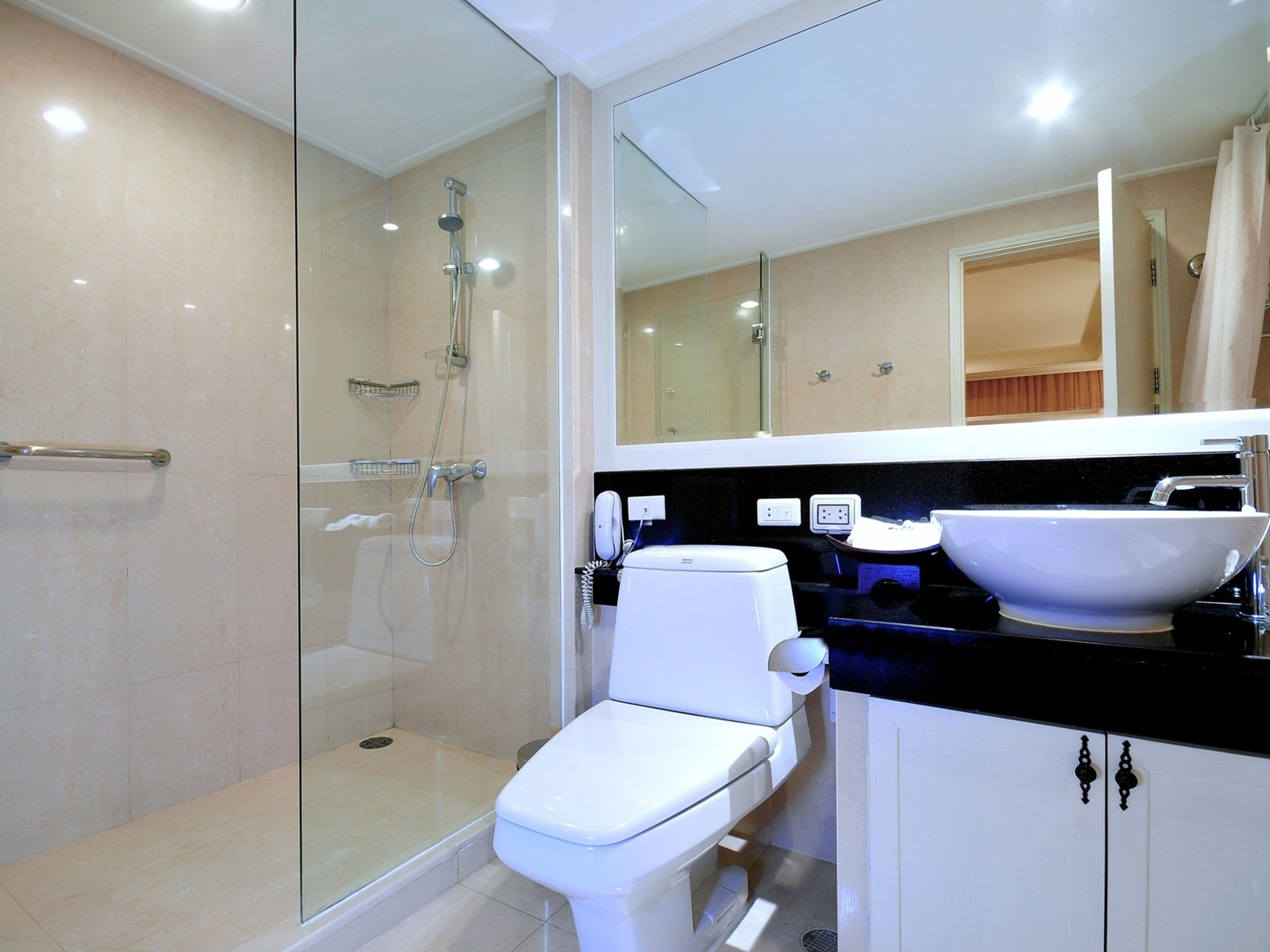 A modern bathroom with a glass-enclosed shower, a white toilet, and a black countertop with a white sink.