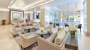 A spacious lobby with a modern chandelier, comfortable seating, and a large mirror reflecting the interior. - Centre Point Sukhumvit 10 (Bangkok)