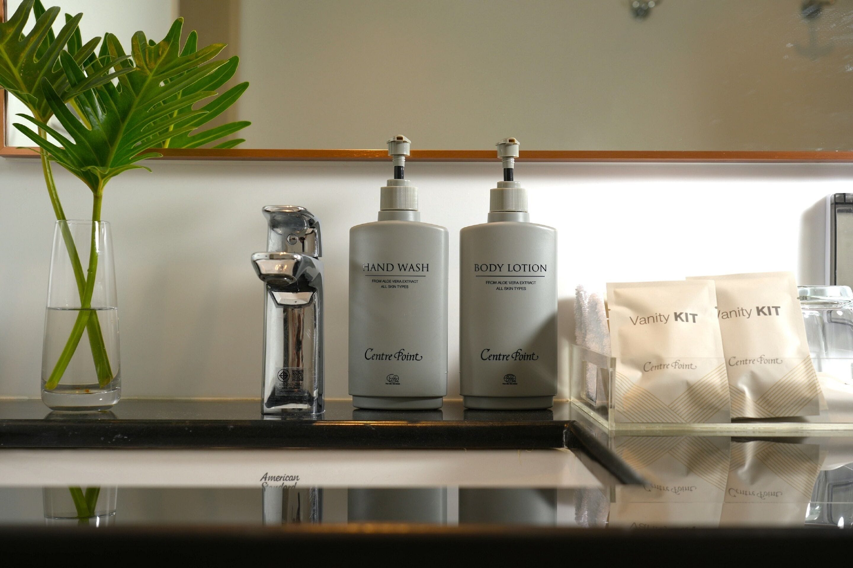 A bathroom counter with a hand soap dispenser, body lotion, and vanity kit.