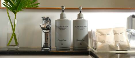 A bathroom counter with a hand soap dispenser, body lotion, and vanity kit.