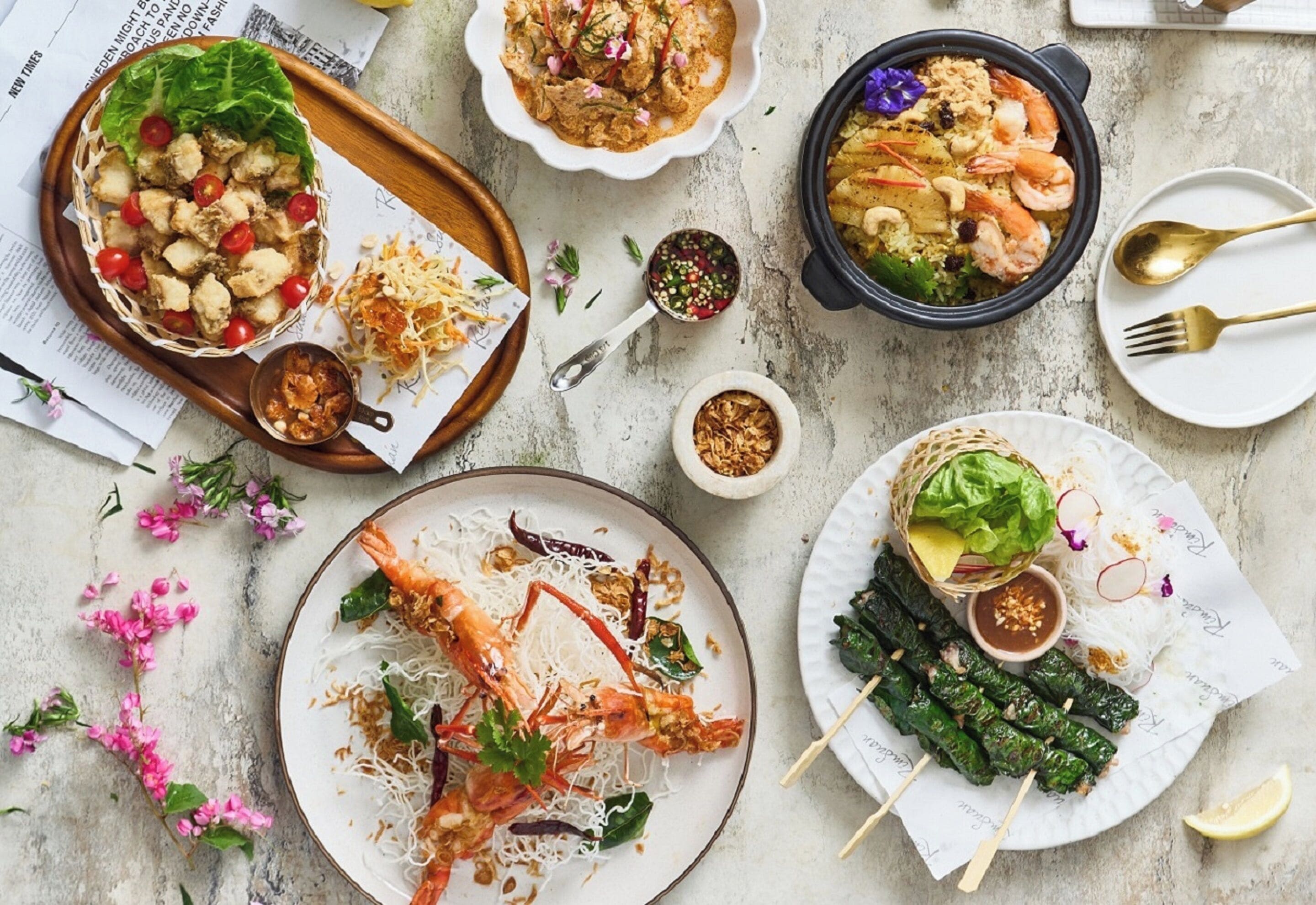 A table with various dishes including shrimp, noodles, and grilled items, suggesting a meal setting.
