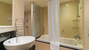 A modern bathroom with a large white sink, a bathtub, and a shower.