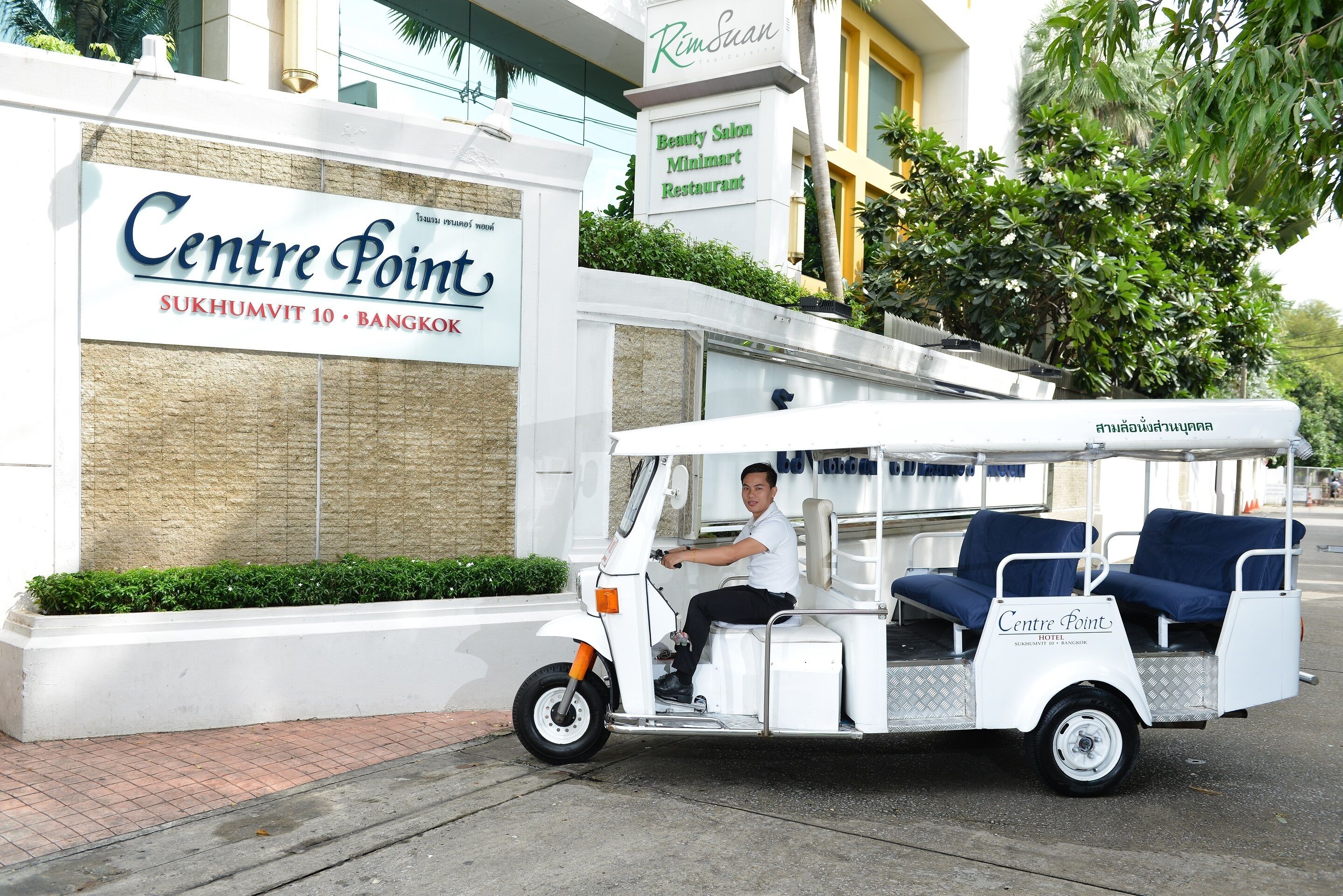 Een golftrolley geparkeerd voor een gebouw met borden voor Centre Point Hotel en een schoonheidssalon.
