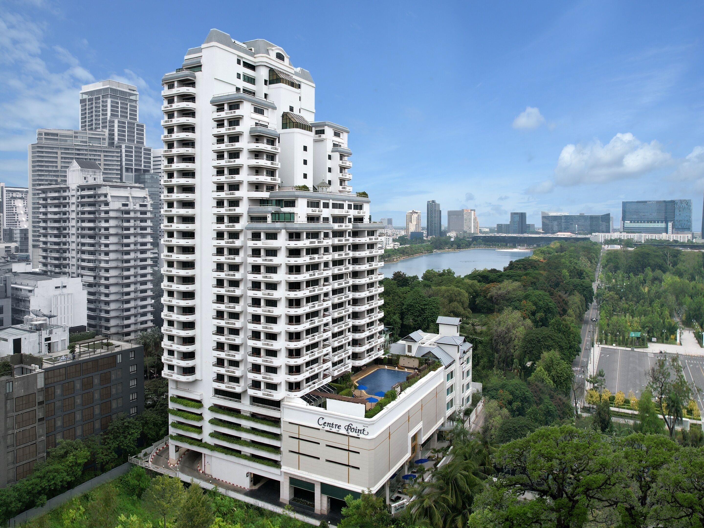 Un hôtel de grande hauteur doté de nombreux balcons, d’une piscine sur le toit et offrant une vue sur une rivière et le paysage urbain.