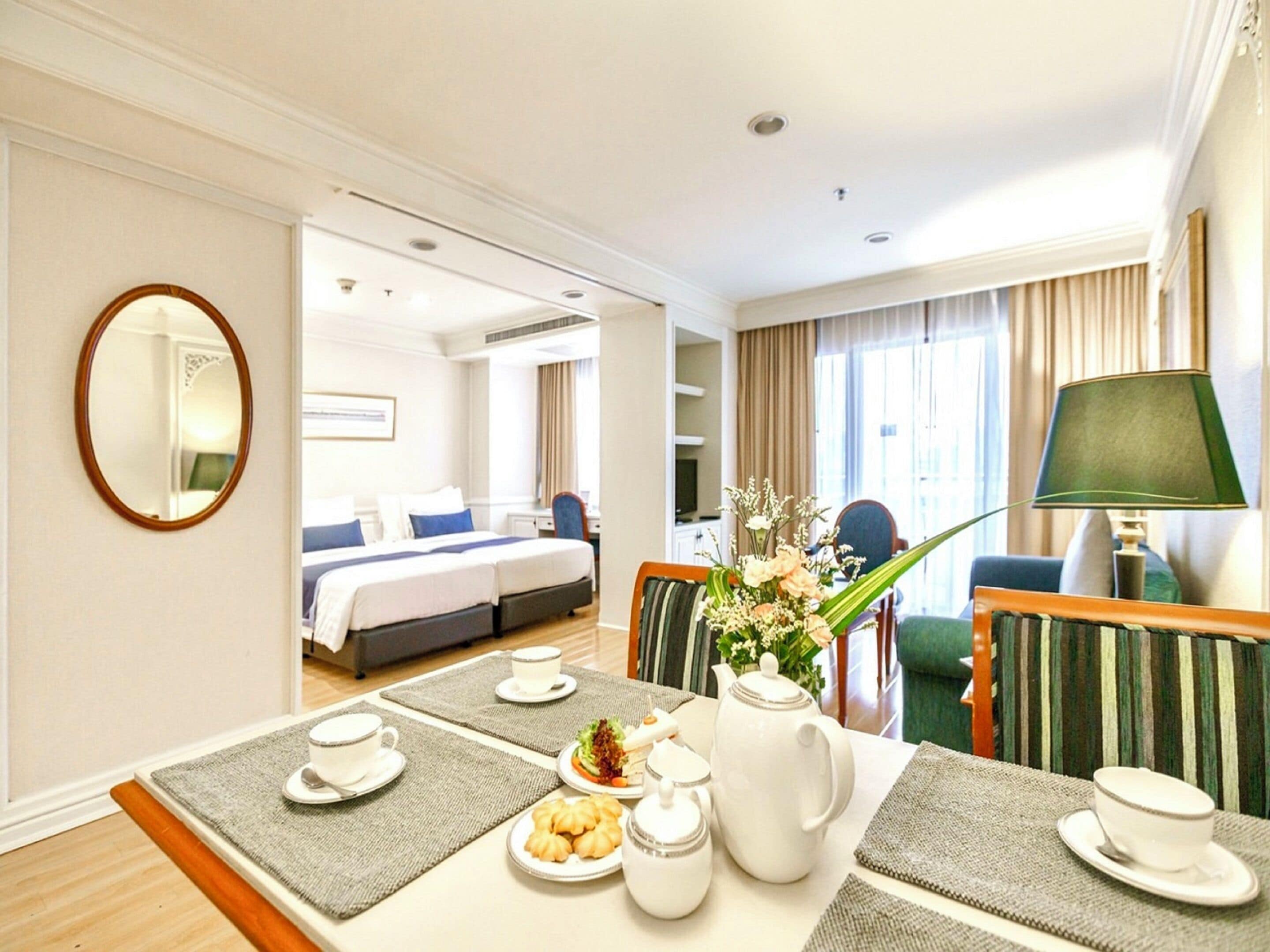 Une chambre d’hôtel comprenant un coin repas, un lit, une télévision et une salle de bain, le tout visible à travers une porte ouverte.