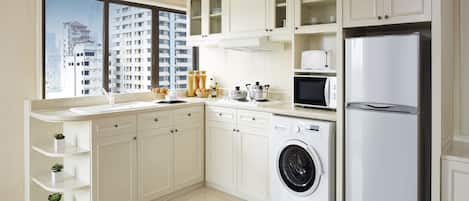 A modern kitchen with white cabinetry, a built-in washing machine, a microwave, and a refrigerator.