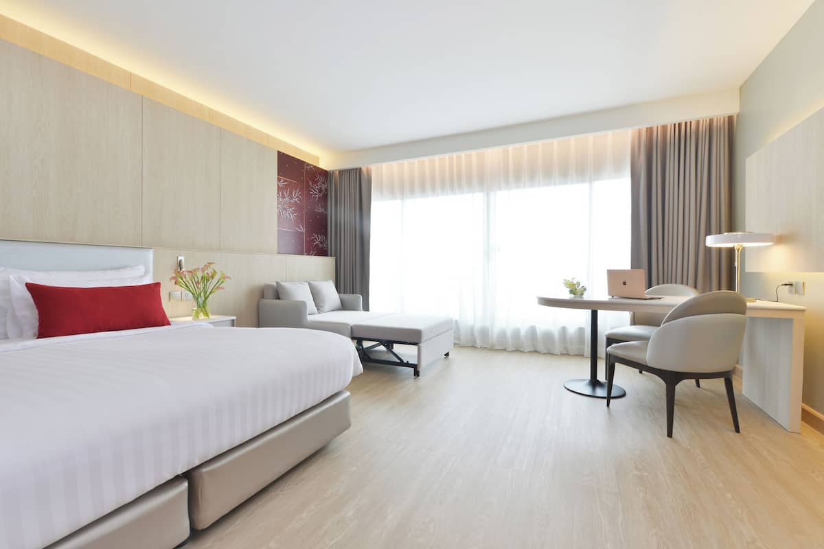 A modern hotel room with a large bed, a desk, and a chair.