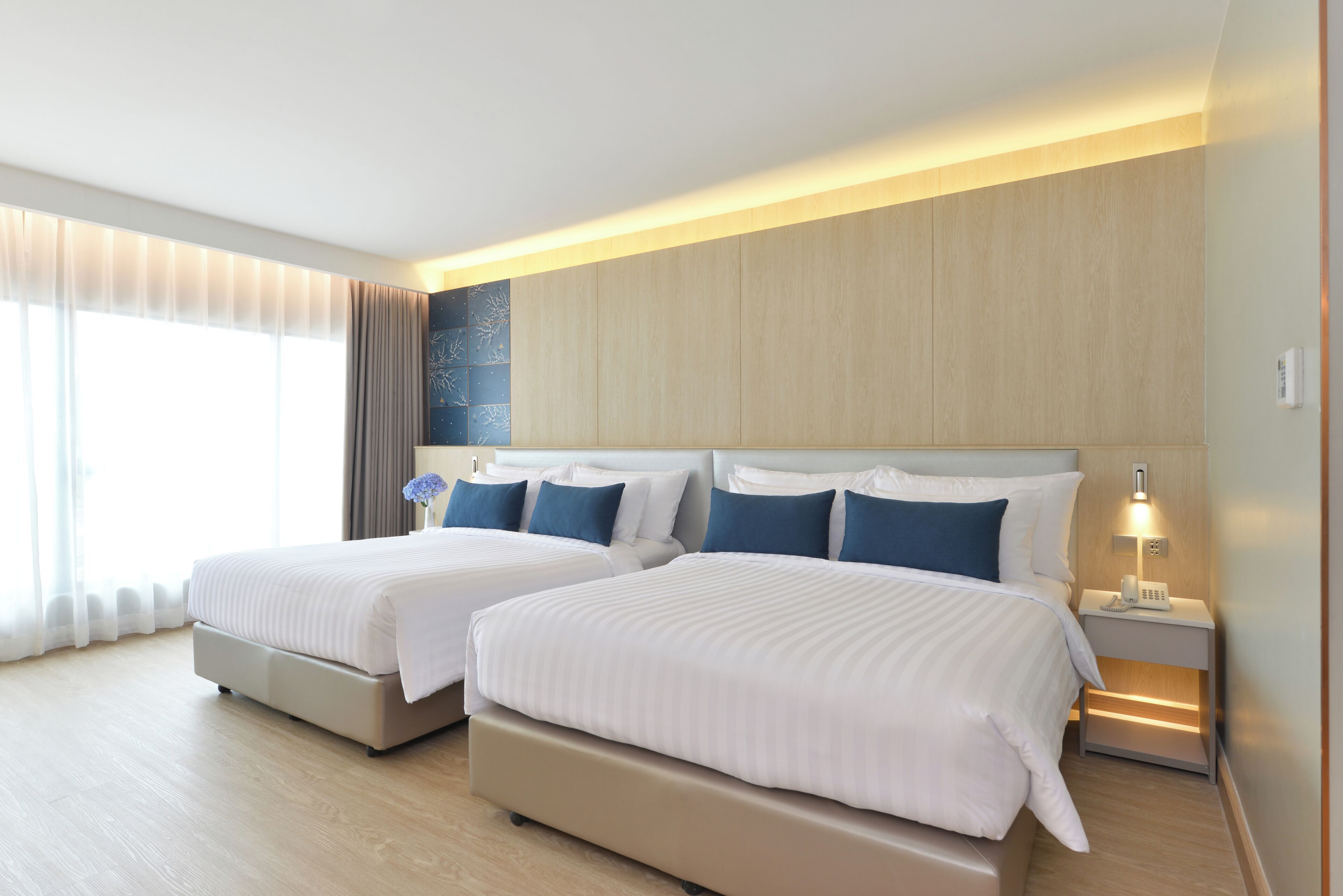 Ein Hotelzimmer mit zwei Betten, einem Nachttisch mit Telefon und einer Wandleuchte.