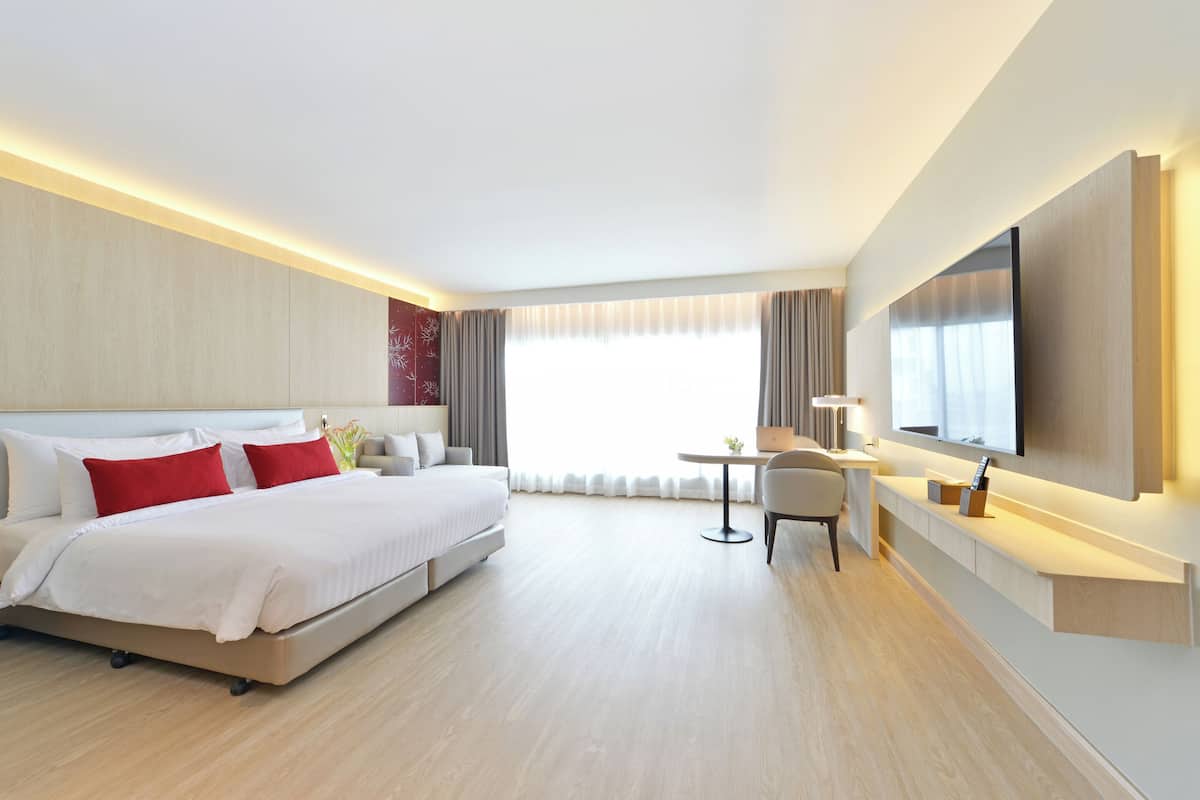 A modern hotel room with a large bed, a desk, and a TV.