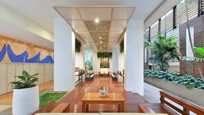 A spacious lobby with a central seating area, a reception desk, and a decorative wall with blue patterns. - Centre Point Plus Hotel Pratunam (Bangkok)