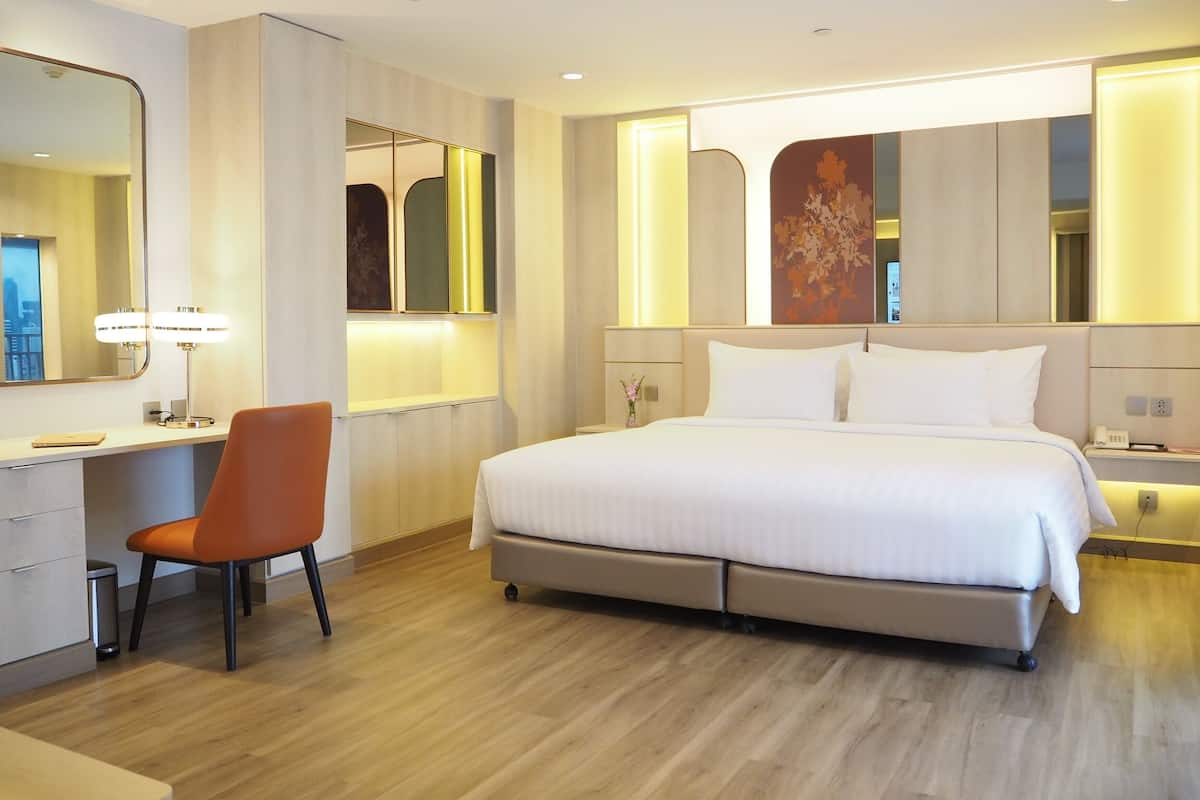 A modern hotel room with a large bed, a desk, and a chair.