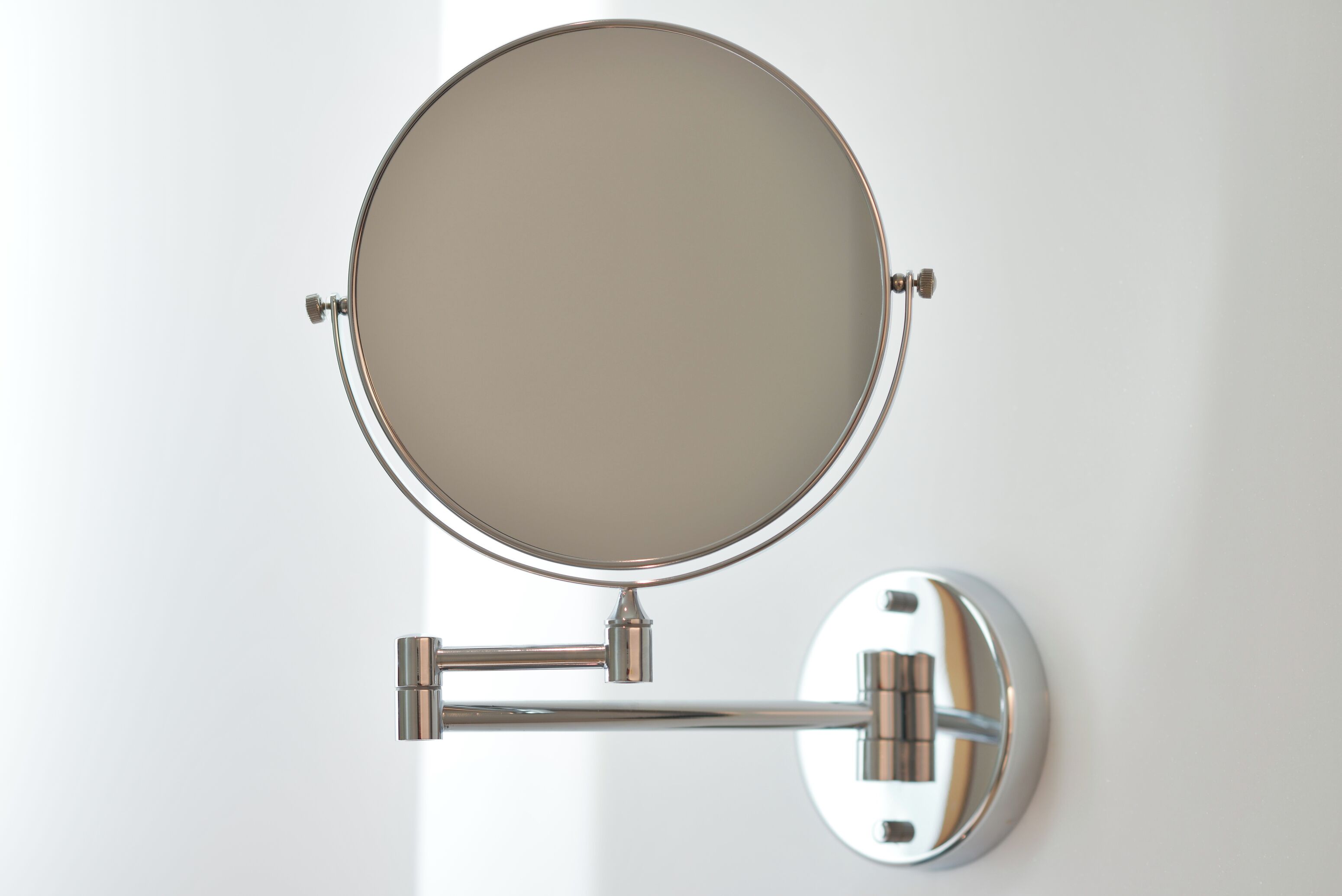 A wall-mounted mirror with a round reflective surface and a metallic frame.