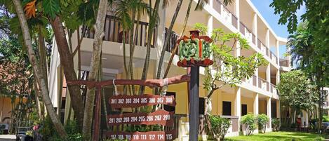 A building with numbered signs, palm trees, and a well-maintained garden.