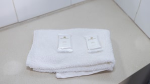A white towel with two small white tubes on a countertop. - Windsor Heritage Motel (Windsor)